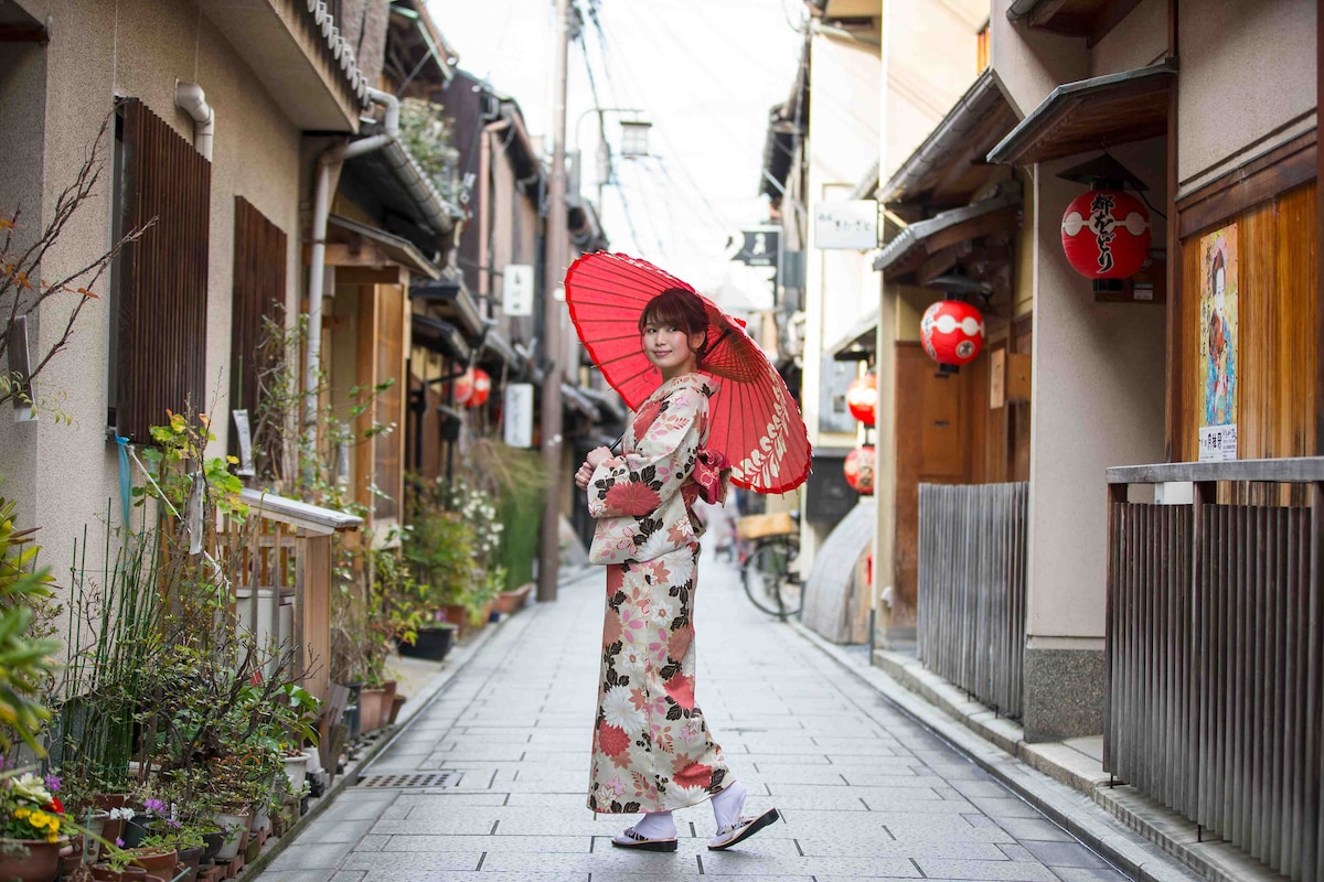 京都花見小路でポーズをとる和傘をさす着物姿の若い女性